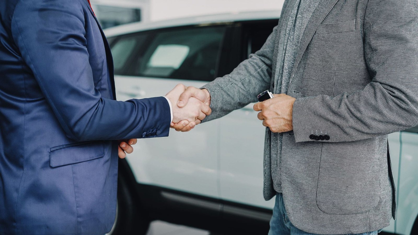 Close-up of two people shaking hands while exchanging car keys