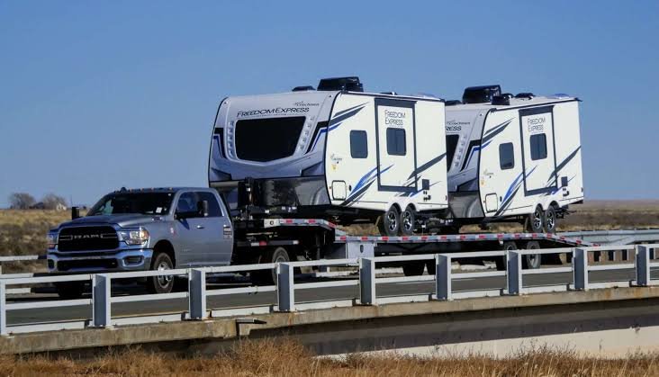 Two travel trailers loaded on a flatbed carrier